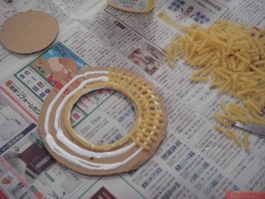 段ボールの型にマカロニをボンドで付けている写真